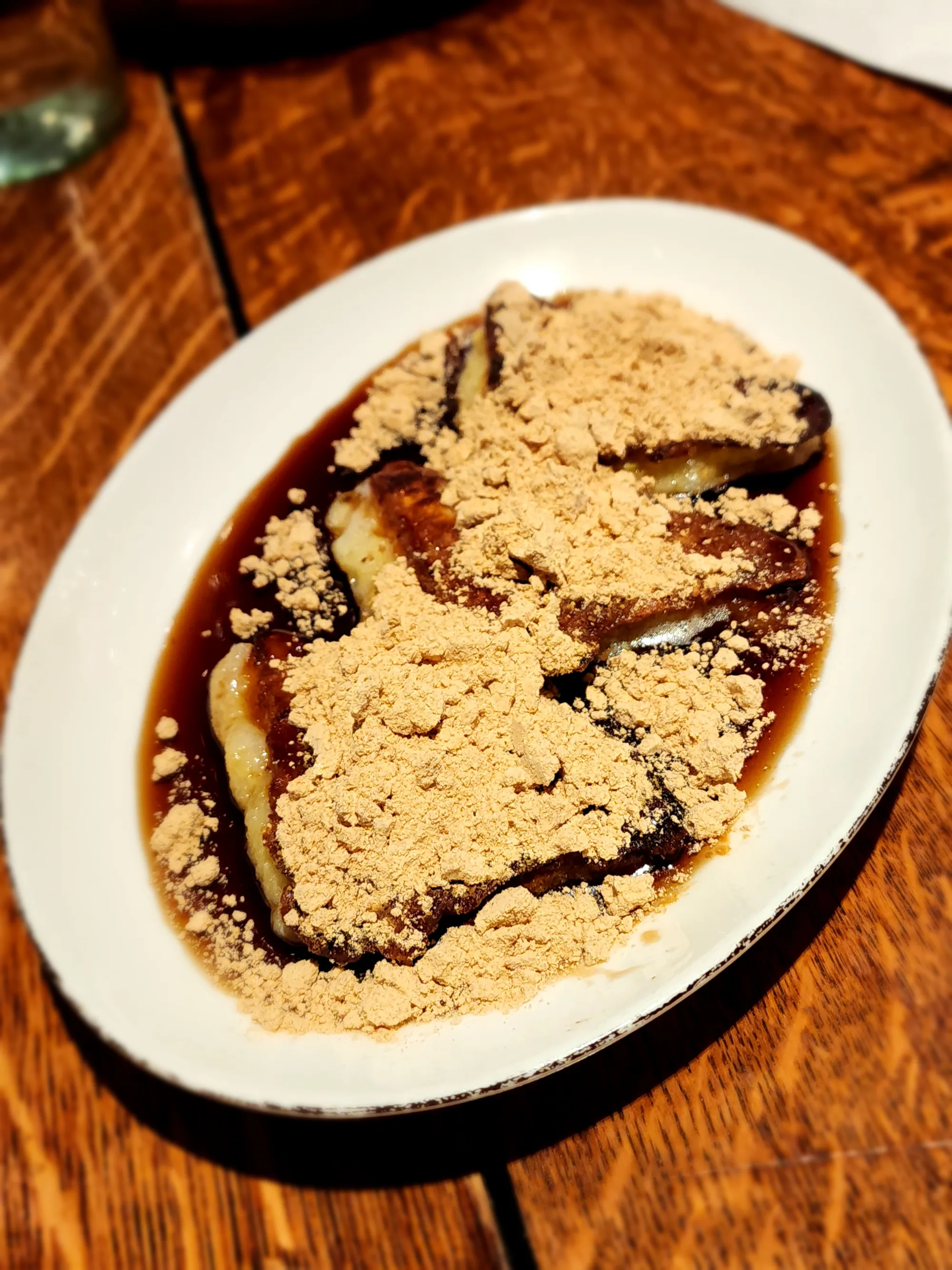 Rectangular rice cakes drizzled with dark syrup on an oval white plate